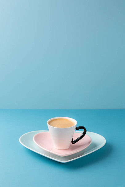 Tazza di caffè su piatto a forma di cuore su sfondo blu. Copia spazio. - Foto, immagini