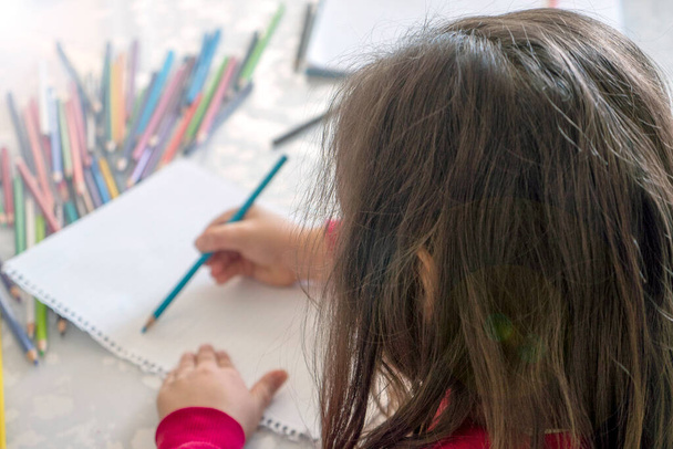 маленька дівчинка розмальовка з олівцями за столом, крупним планом дитячий садок розмальовка
, - Фото, зображення