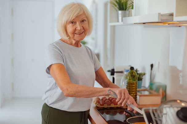 Mujer anciana cocinando comida en la cocina en casa - Foto, Imagen
