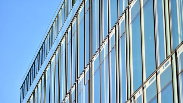 都市抽象-オフィスビルの窓壁。市内の近代的なビジネスビルの詳細ショット。超高層ビルのガラスのファサードを見上げ. - 写真・画像