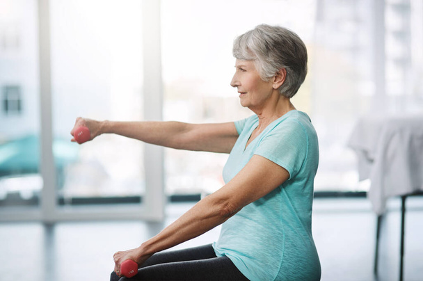 Working on keeping herself healthy. Cropped shot of a healthy senior woman working out with dumbbells. - Foto, imagen