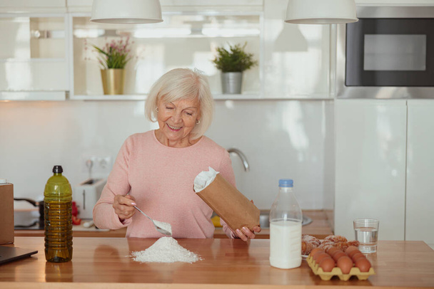 Mujer jubilada sonriente disfrutando de cocinar en casa - Foto, Imagen