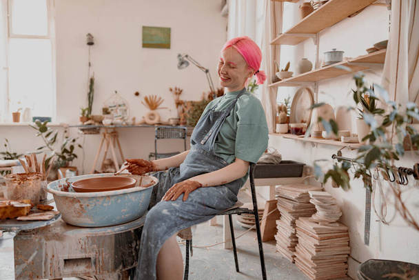 Cute potter creating ceramic bowl on circle in workroom - Photo, Image