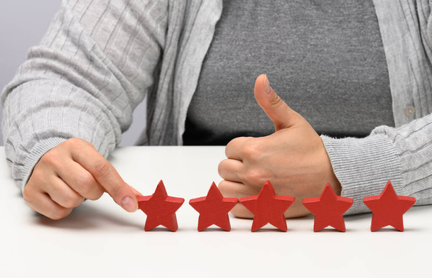 Customer experience feedback concept. Five red stars, the best rating of excellent services with a female hand to meet. White table - Photo, Image