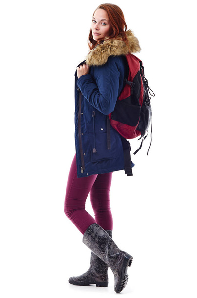 Warm und stilvoll bleiben. Studioporträt einer jungen Frau in Winterbekleidung und mit einem Rucksack vor weißem Hintergrund. - Foto, Bild