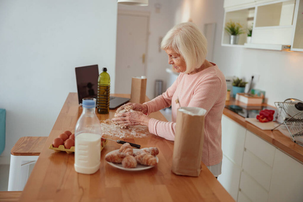 Ahkera ikäinen nainen ruoanlaitto kotona keittiö - Valokuva, kuva