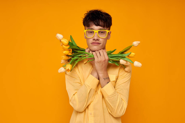 A young man in yellow glasses with a bouquet of flowers holiday unaltered - Foto, Bild