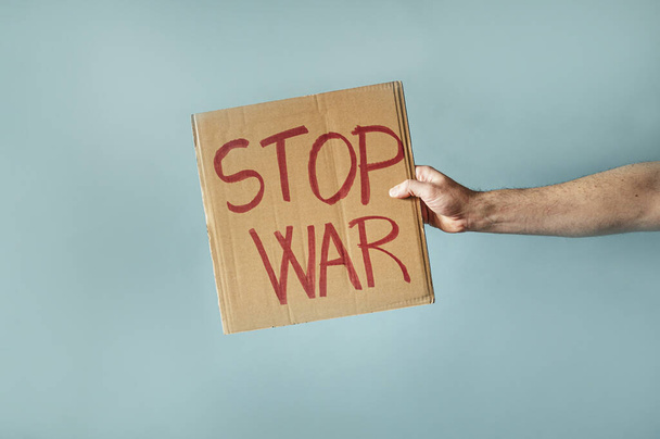 Kézen fogva egy táblát, amire az van írva, hogy STOP WAR. - Fotó, kép