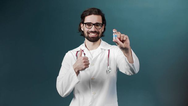 A young doctor shows an ampule with vaccine - 写真・画像