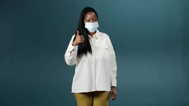 Una atractiva dama africana alegre se está poniendo máscara médica para la protección de la salud y la prevención durante el brote del virus, las enfermedades epidémicas e infecciosas - Foto, imagen