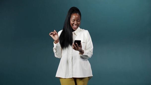 Egy csinos afrikai lány fehér blúzban szelfit készít, fotókat választ és mosolyog. - Fotó, kép