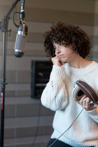 Eine junge Sängerin mit lockigem Haar macht sich im Tonstudio Sorgen - Foto, Bild