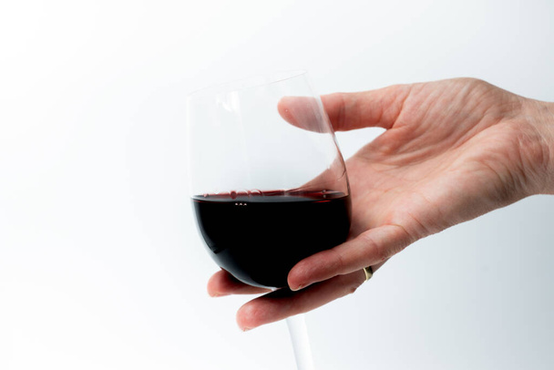 χέρι γυναίκας κρατώντας ένα ποτήρι κόκκινο κρασί που απομονώνονται σε λευκό, αλκοολισμός - Φωτογραφία, εικόνα