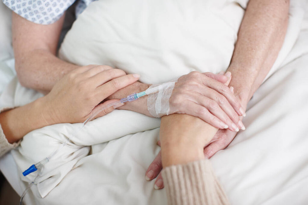 Comforting a sick family member. Cropped image of an affectionate daughters hand being held by her mother in the hospital. - Foto, afbeelding