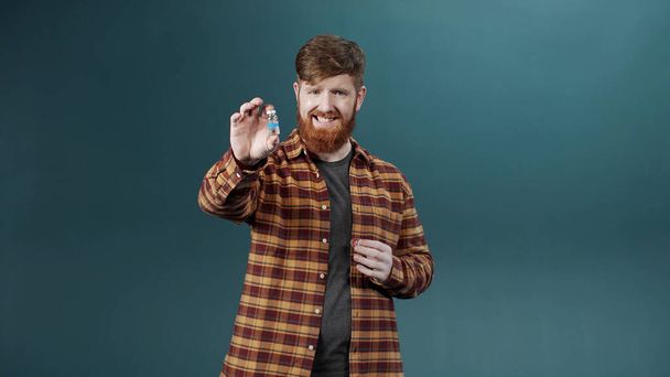 Ein attraktiver junger Mann zeigt zwei Ampullen mit Impfstoff und wählt einen linken - Foto, Bild