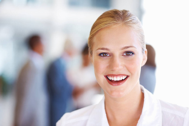 Cheerful young business woman. Closeup of cheerful young business woman with executives in background. - Photo, image