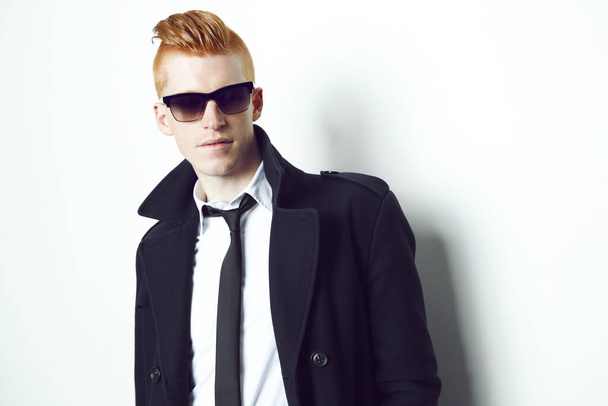 Feeling stylish. A red haired male looking at the camera in a suit and sunglasses with a white background. - Фото, изображение