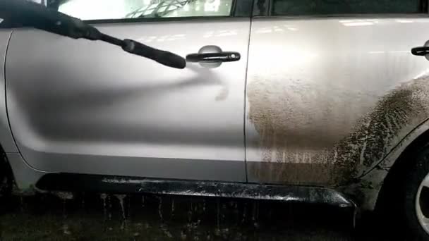 Laveuse de voiture laveuse de machine à laver une voiture sale avec de l'eau haute pression à l'intérieur. Une voiture sale est nettoyée avec un jet d'eau propre à haute pression par une laveuse. - Séquence, vidéo