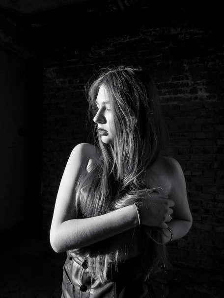 Young sexy woman posing topless against a brick wall, black and white image, nude,aesthetics and beauty of the female body - Photo, Image