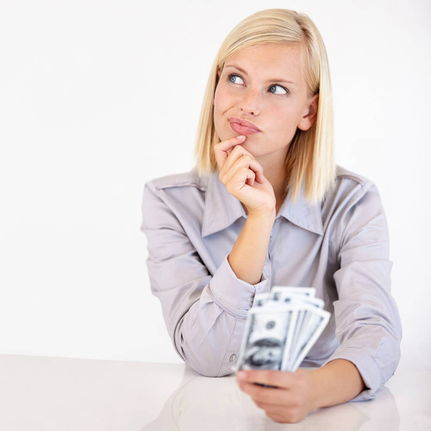 Deciding what to do with her money. A pretty young woman wondering what to do with her cash. - Foto, imagen