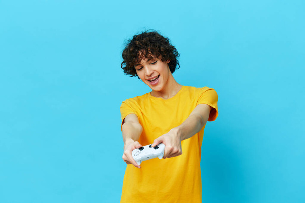 bouclé gars joue avec joystick en jaune t-shirts milieux isolés - Photo, image
