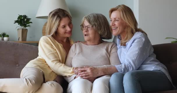 Three generation women having pleasant conversation seated on sofa - Materiał filmowy, wideo
