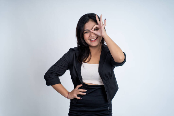 Young woman showing oke gesture with eye looks imitating binoculars - Фото, зображення