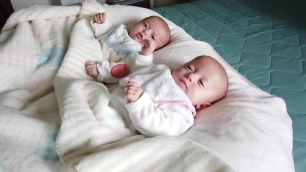 Dos hermanas se acuestan en la cama. Dos bebés gemelos en la cama. - Imágenes, Vídeo