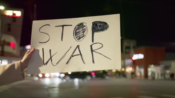 Slow motion outdoor closeup van vrouwelijke activisten hand met STOP de WAR poster - Video