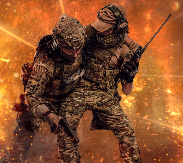 Bestrijding van conflict, speciale missie. De militaire soldaat uitvoering teamgenoot van het slagveld. Studio foto tegen een donkere muur - Foto, afbeelding