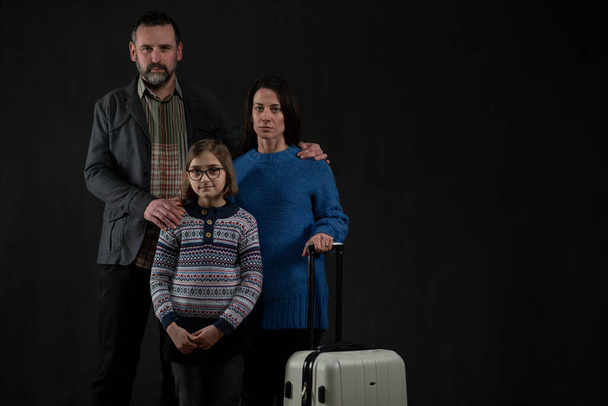 Refugee family with one child looking at camera on black background, Ukraine war concept. - Foto, immagini