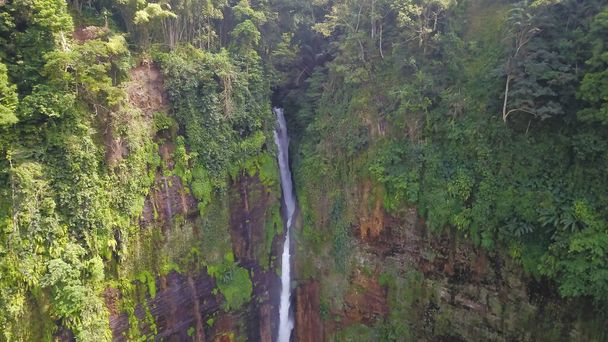 Drone shot Kapas Biru Waterfall is a hidden paradise in Lumajang, East Java with a height of about 90 meters, the water is very heavy and clear - Photo, Image