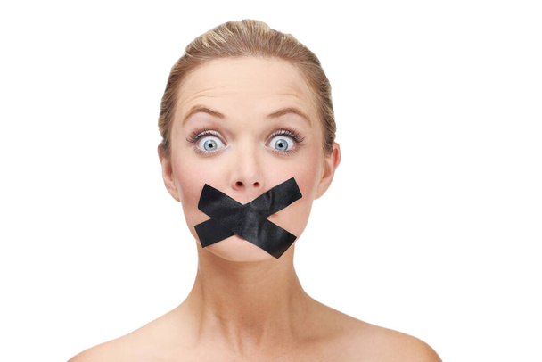 Silenced by the system. A young blonde woman looking shocked with duct tape covering her mouth. - Photo, Image