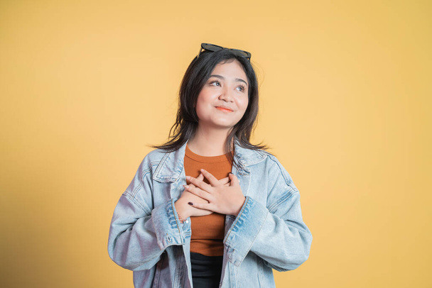 Asian young woman holding chest while feeling relieved - Фото, изображение