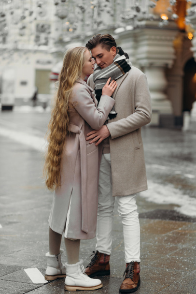 liefdesverhaal paar liefde jas beige grijs wit boeket van bloemen tederheid gevoelens lopen knuffel date - Foto, afbeelding
