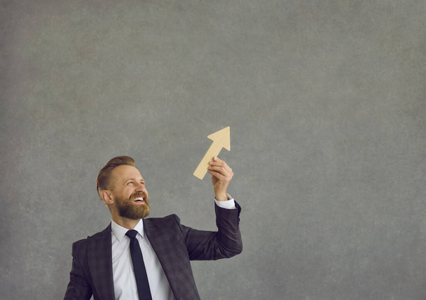 Happy businessman holding arrow going up as metaphor for business growth and success - Foto, Imagem
