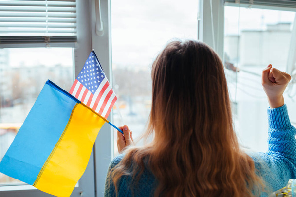 Woman holding ukrainian and american flags during war with Russia. USA support sanctions. Invasion in Ukraine. 2022 Russian attack of Ukraine - Photo, Image