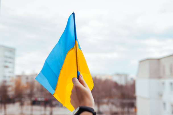 Γυναίκα κρατώντας την ουκρανική κίτρινη και μπλε σημαία κατά τη διάρκεια του πολέμου με τη Ρωσία. Εισβολή στην Ουκρανία. 2022 Ρωσική επίθεση της Ουκρανίας. Σύμβολο πατριωτισμού - Φωτογραφία, εικόνα