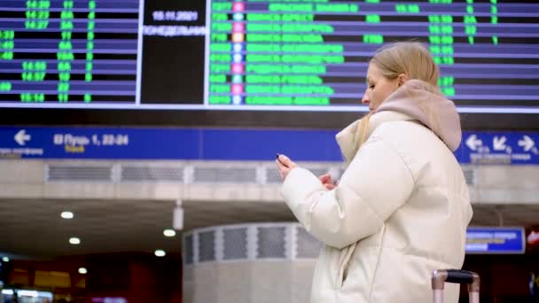 Женщина наблюдает за прибытием и проверяет рейс - Кадры, видео