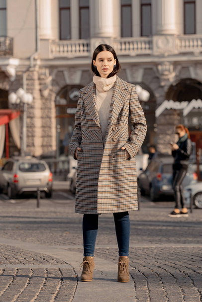 Дивна дівчина йде по вулиці в європейському місті в стильному пальто. - Фото, зображення