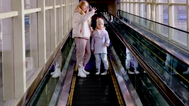  Mom and daughter go down the escalator from the station building to the platform - Footage, Video