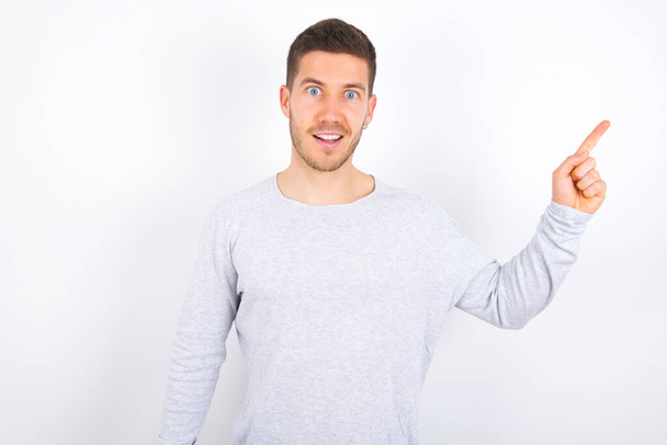 young caucasian man wearing casual clothes over white background points aside on copy blank space. People promotion and advertising concept - Foto, imagen