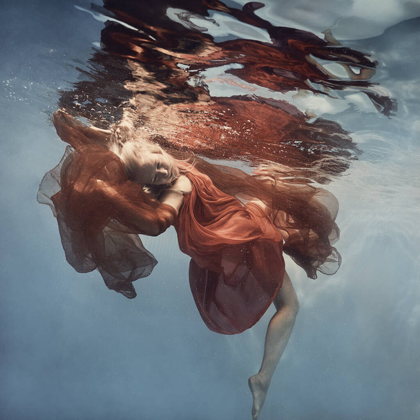     A woman in a dress swims underwater as if floating in zero gravity                            - Zdjęcie, obraz