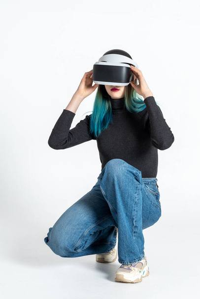 A teenager girl puts on a vr helmet to enter the virtual universe isolated on a white background. Lifestyle in the virtual space - Foto, immagini
