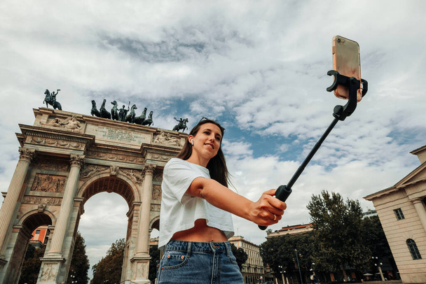 Travel influencers Milan island. Paint building house in Europe Milano. Photographer blogger girl with smartphone in Piazza del Duomo, Cathedral Square. Traveling and freelancing, modern lifestyle - Photo, Image
