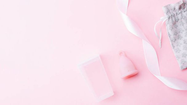 Menstrual cycle sanitary cup. Pink ribbon with menstrual cup. Menstruation feminine period. Sanitary hygiene banner. Use menstrual cup inside vagina - Фото, изображение