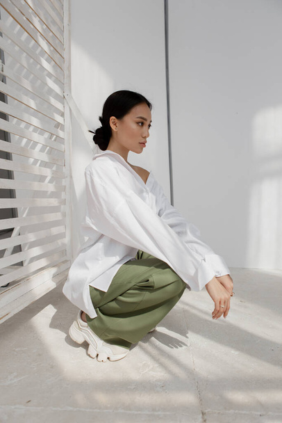 Krásná a stylová dívka s asijským vzhledem v minimalistickém interiéru - Fotografie, Obrázek