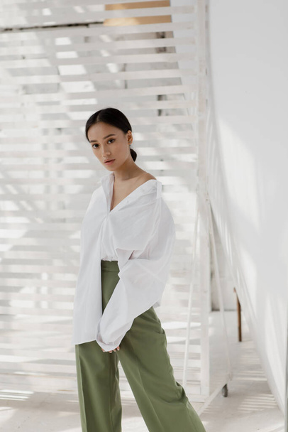 Mooi en stijlvol meisje met Aziatische uitstraling in een minimalistisch interieur - Foto, afbeelding