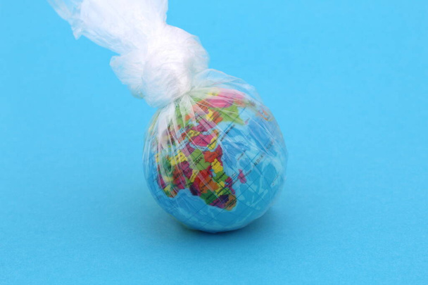 There is a globe on a blue background. The model is stuffed into a salafan bag. - Zdjęcie, obraz