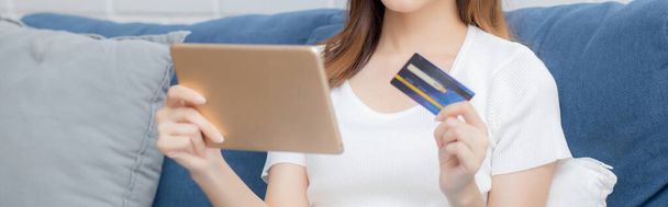 Młoda azjatycka kobieta uśmiechnięta trzymając karty kredytowe zakupy online z tabletem zakup i płatność, dziewczyna przy użyciu karty debetowej zakupu lub transakcji finansowania, styl życia i e-commerce koncepcji. - Zdjęcie, obraz